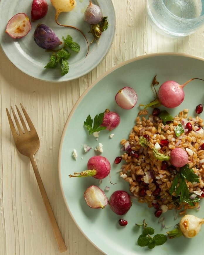Roasted Radishes & Farro with Mint Lime Vinaigrette Roasted Radishes & Farro with Mint Lime Vinaigrette sits on a green plate with a gold fork positioned to the left. A farro dish