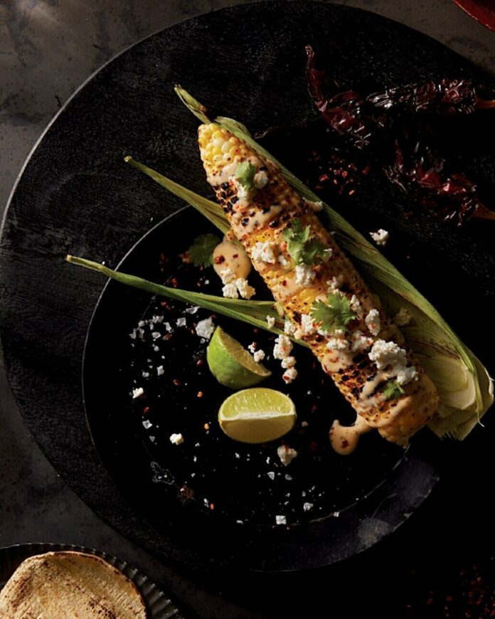 An aerial shot of an ear of spicy mexican street corn sitting on a black plate. Where to Find Fresh Summer Sweet Corn in Pittsburgh