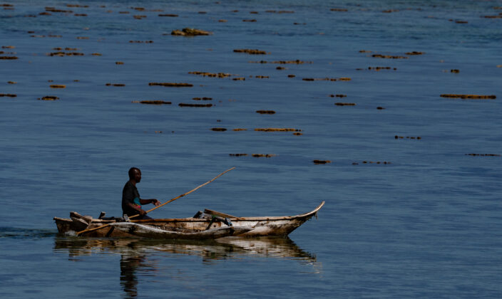 An African man in Zanzibar rows a handmade boat