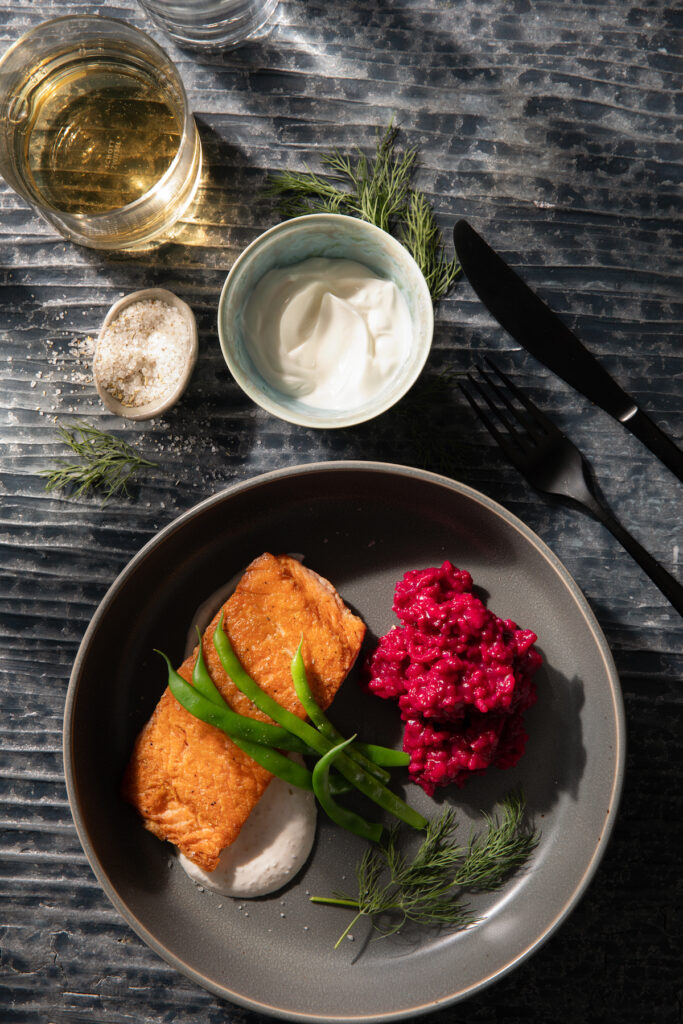 Seared Salmon with Borscht Risotto and Horseradish Crème Fraîche sits in a grey plate with high edges. Seared Salmon recipe