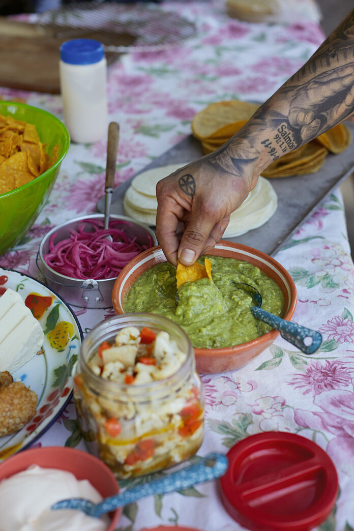 A hand sticks a chip in a green dip
