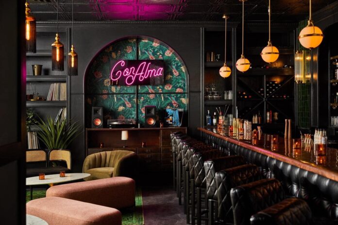 Con Alma Inside of Con Alma, a neon Con Alma hangs on the wall against a colorful wallpaper