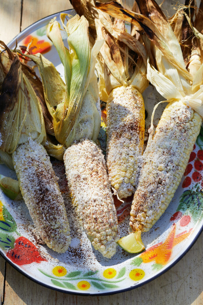 4 Elotes covered in roasted Garlic Butter sit on a paper plate. Elotes recipe