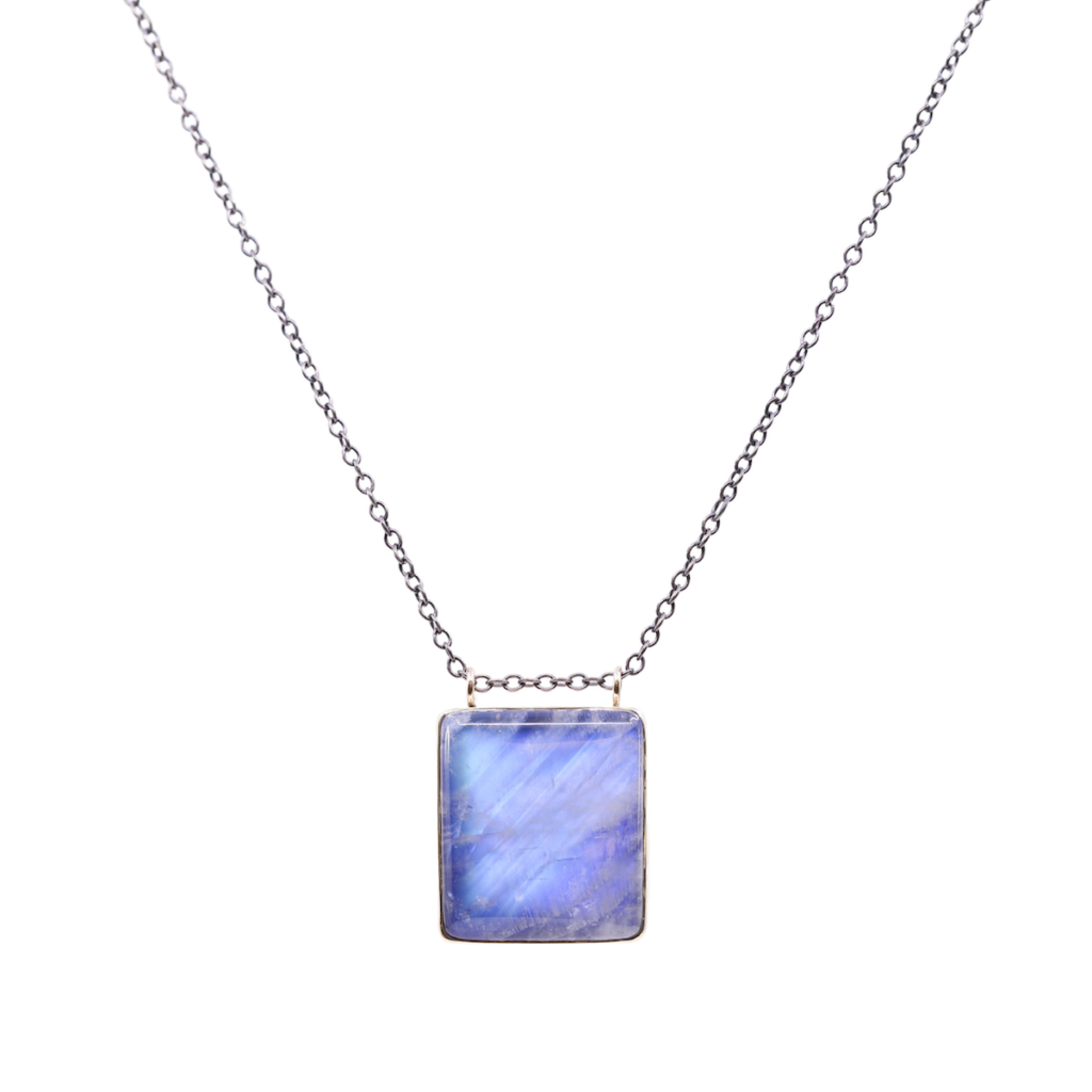smooth blue rainbow moonstone surrounded by a filament of 14K yellow gold and suspended on an oxidized sterling silver chain. 2023 fall winter trends