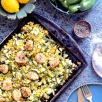 A sheet pan filled with Summer Scallops and Corn. To the side sits bowls of peppers, lemon, and salt. Scallops recipe