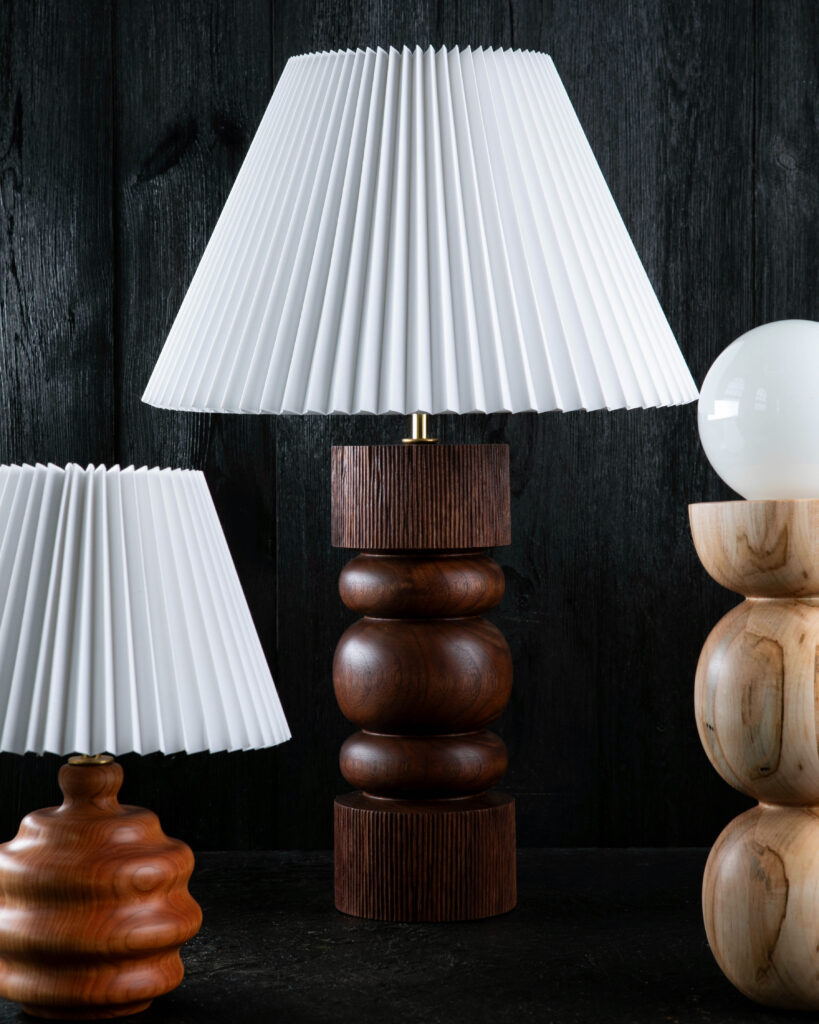 Shown, left to right, mini table lamp in cherry, carved walnut table lamp, and bulb table lamp in ambrosia maple. 