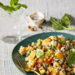 A teal speckled serving dish white background and a large portion on quinoa and peach salad.