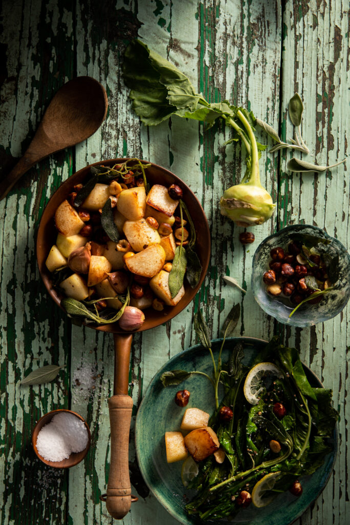 Flat-lay image of a pan of roasted kohlrabi resting on weathered wood table.