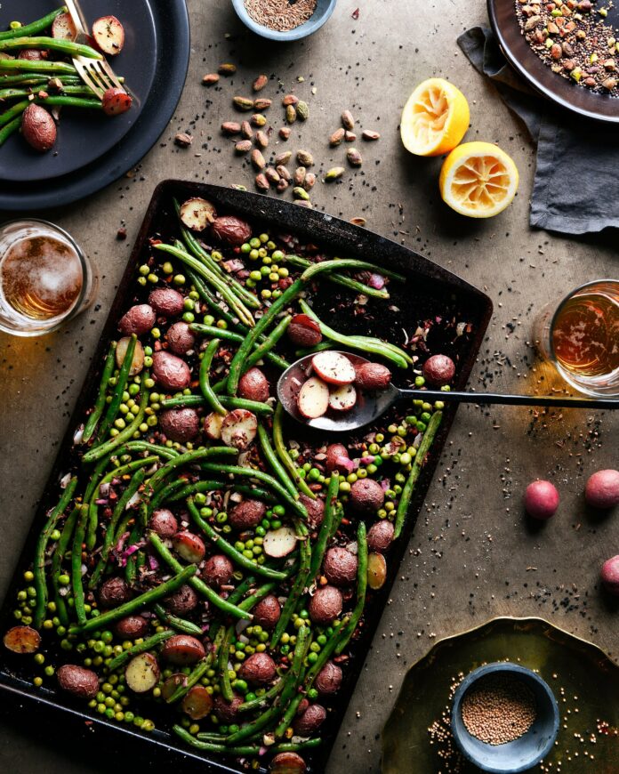 Easy Bake Beans and Potatoes An aerial shot of a sheet pan covered in green beans and potatoes.