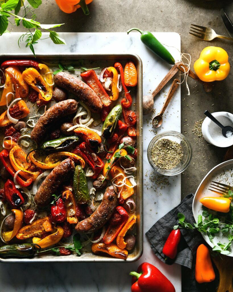 An aerial view of a sheet pan filled with Sausage and red, orange, and yellow peppers.