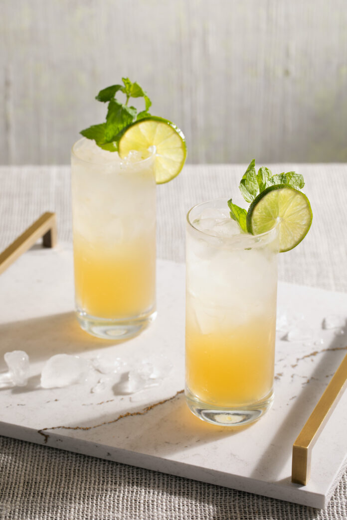 Eva Longoria Inspired Mojito Recipe Two mojito cocktails, clear on top and yellow on the bottom, in highball glasses and garnished with lime wedges and mint. Mojito Recipe