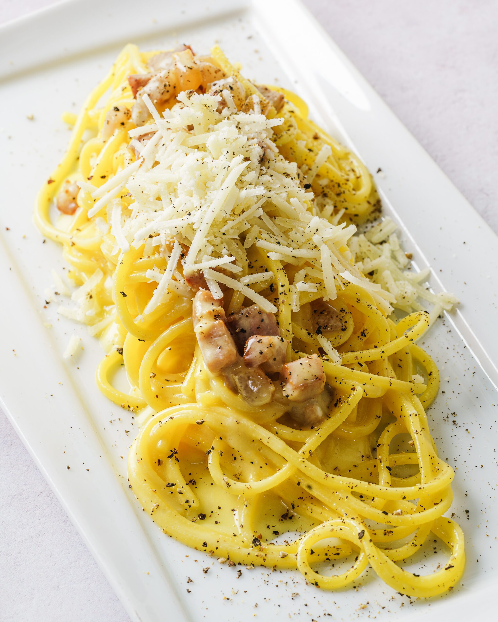 A plate of bucatini with squash blossom on top of it