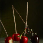 Red, candied apples sitting on a dark table, one apple has a bite taken out of it