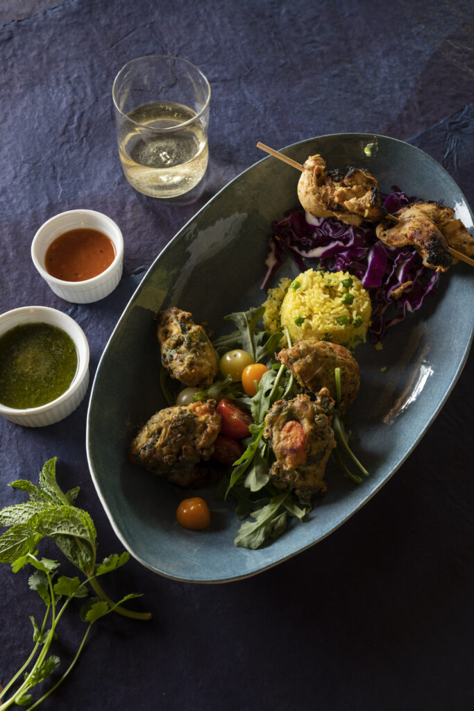 Crispy Chile Pakora Fritters with Spinach, Onion, and Aromatic Spices, Served with Cilantro-Mint Chutney and Chicken Malai Kabab