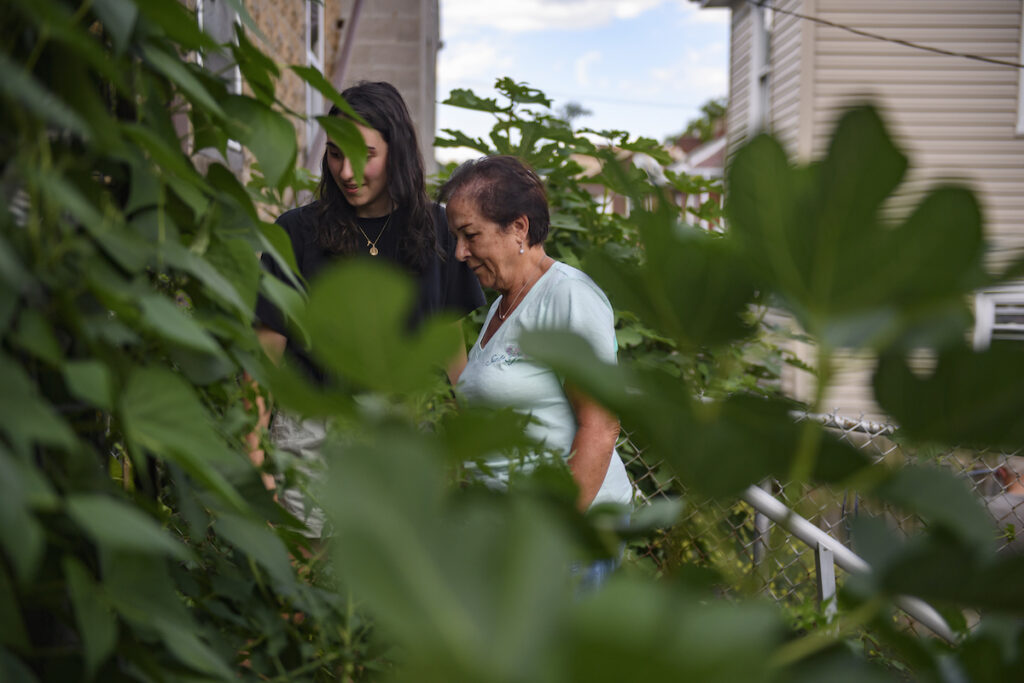 two women mostly covered by green leaves