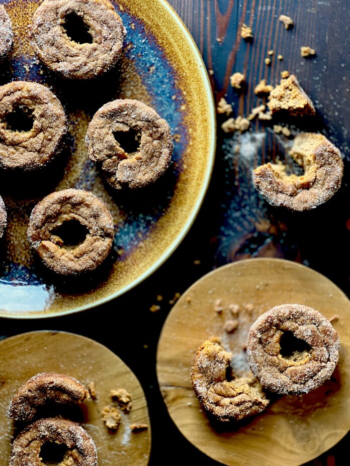 An aerial view of six keto pumpkin donuts sit on three plates