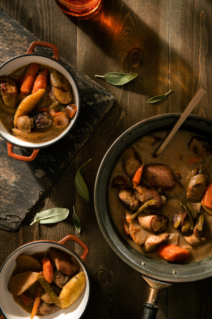On the right of the frame is a big bowl of beer brat stew. On the left sits two bowls of the stew. fall recipes