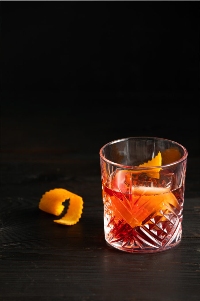 Negroni Con Alma Recipe A light red cocktail in a rocks glass with an orange peel inside the glass. Negroni Con Alma Recipe