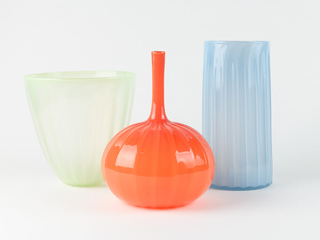 Three glass vases: green, orange, and blue, respectively 