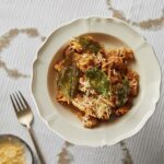 A bowl of carrot Bolognese on a white tablecloth with 3 beige circles.