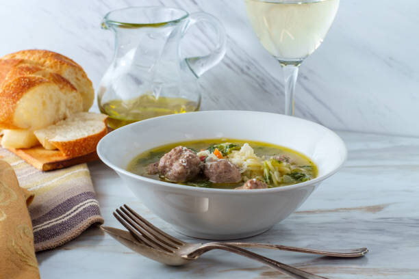 A steaming bowl of Vegetarian Italian Wedding Soup with Impossible Burger meatballs, served in a comforting broth with orzo pasta and fresh escarole.