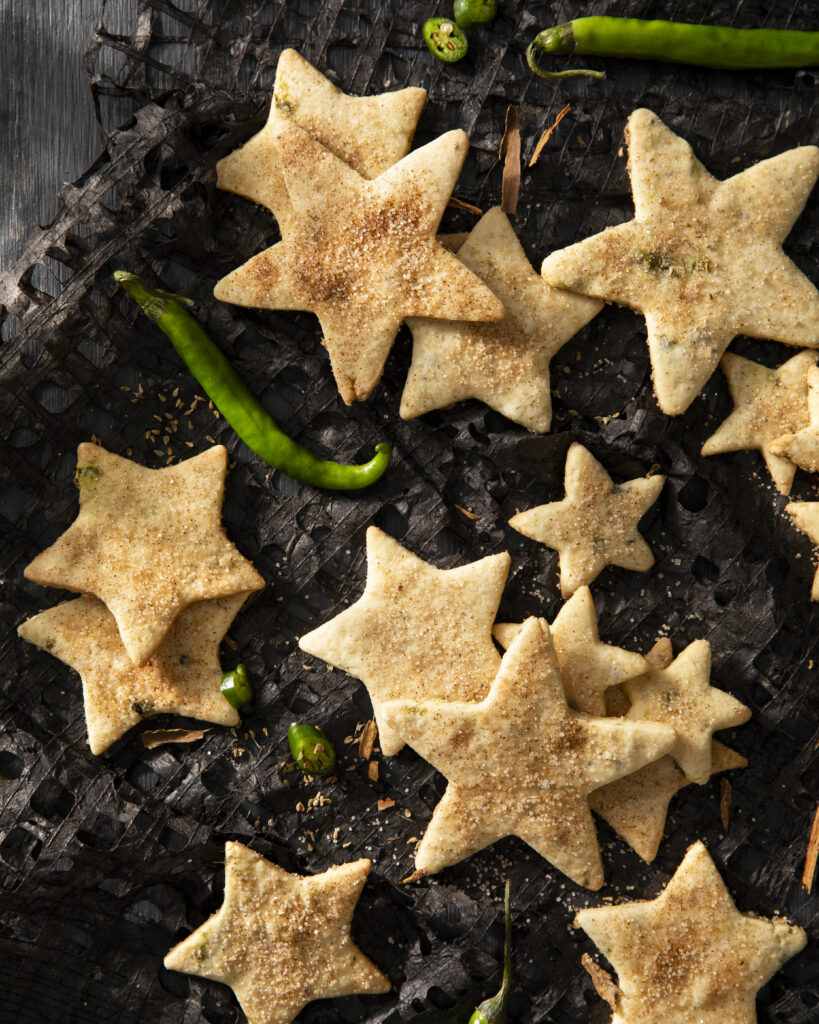 Green chile biscochitos cut into star shapes with green chiles decorating the plate. Biscochitos recipe