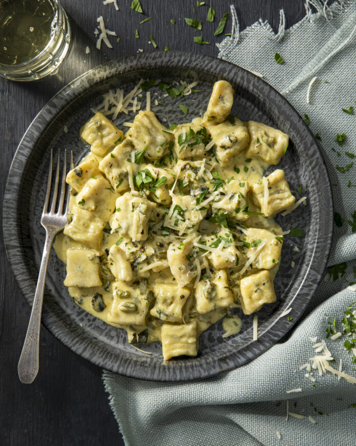 Plated ricotta gnocchi in a roasted green chile sauce topped with parmesan cheese.