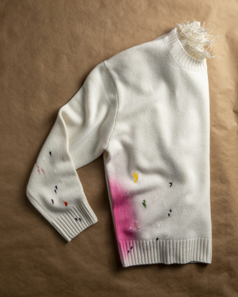pink hand painted design on a white sweater. handmade trend 2023