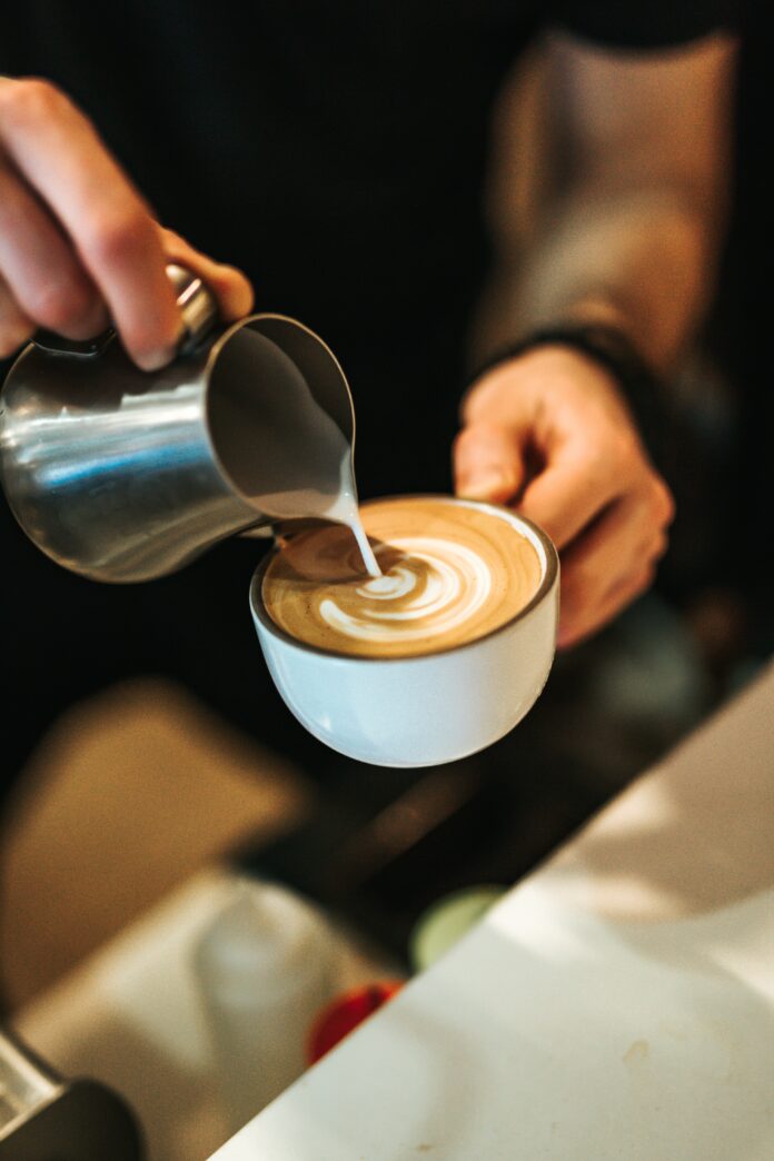 A pair of white hands pours milk into an espresso. National Coffee Day. Pittsburgh Coffee Shops Pittsburgh Cafes