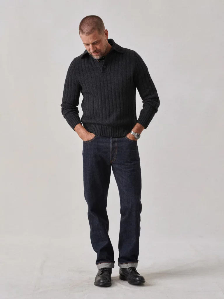 A man modeling a dark navy sweater with his hands in his pockets.