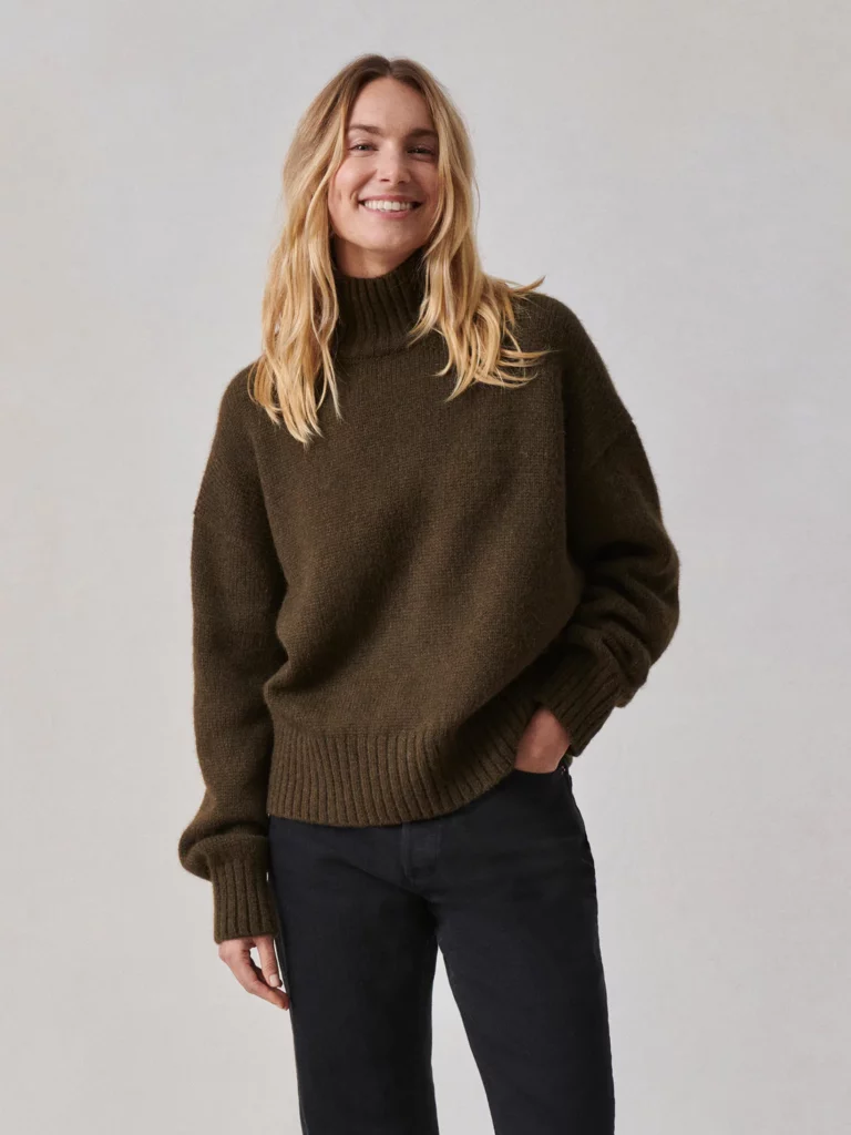 A woman with blonde hair in a brown sweater turtleneck.