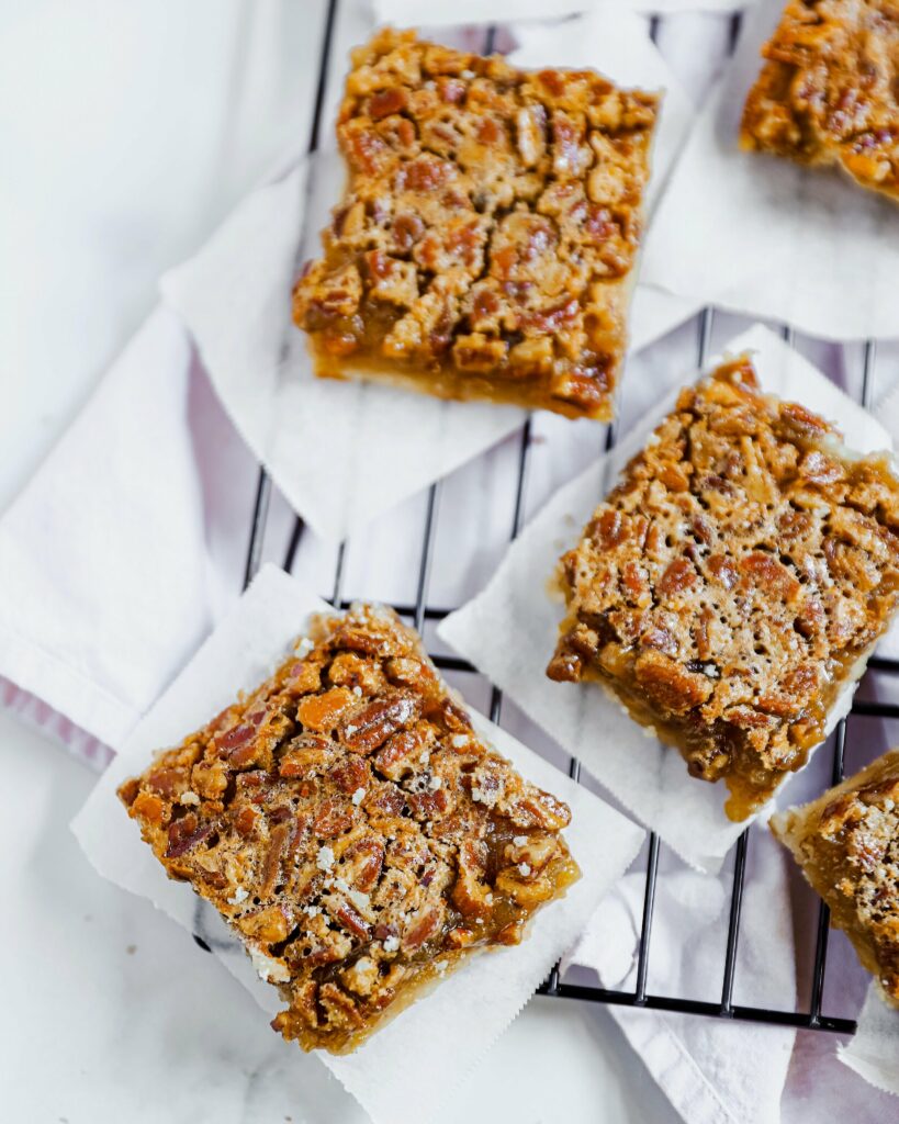 An aerial shot of four pecan pie bars sitting on a wire cooling rack.