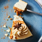 Caramel drizzle a top of a slice of caramel apple cheesecake, broken up on a blue plate.