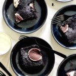 An aerial shot of four black plates, each with a piece of Fudgy Peppermint Patty Brownies sitting on them. Fudgy Peppermint Patty Brownies recipe
