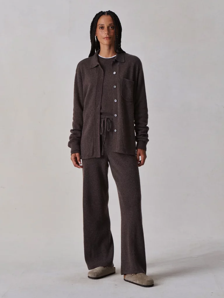 A woman with black hair in a brown button-up lounge shirt and pants.