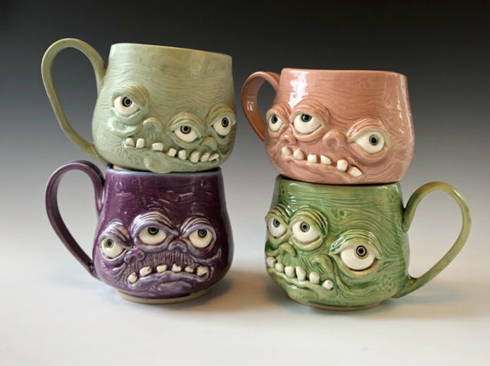 Four monster-looking pottery mugs painted green, pink, purple, and grey.