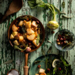 Flat-lay image of a pan of roasted kohlrabi resting on weathered wood table.