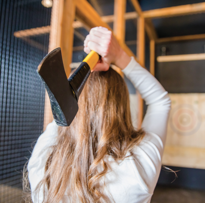 A women throwing an axe at an axe throwing bar. Indoor Activities Pittsburgh