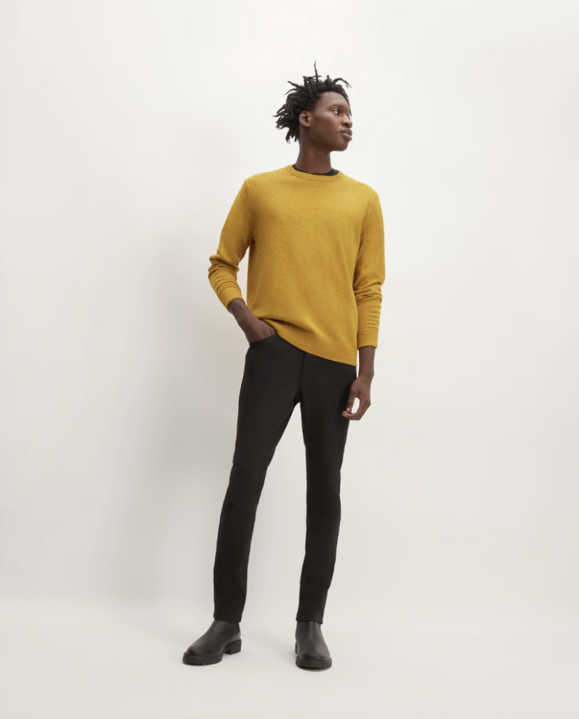 A black man wears a gold sweater with black pants