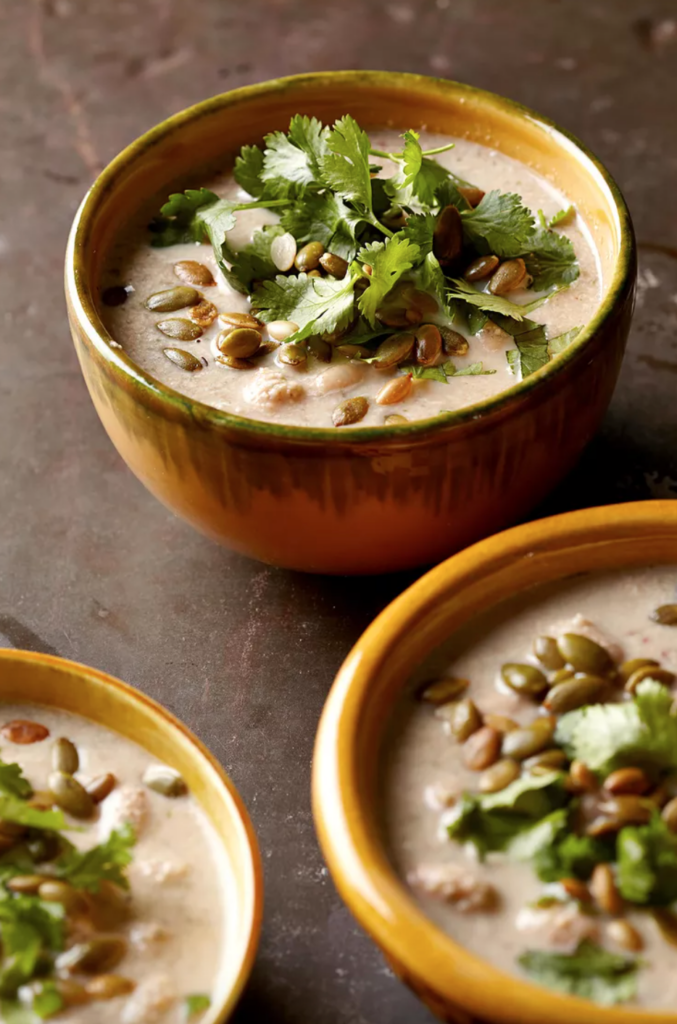 Pumpkin seed soup in colorful bowls garnished with parsley.