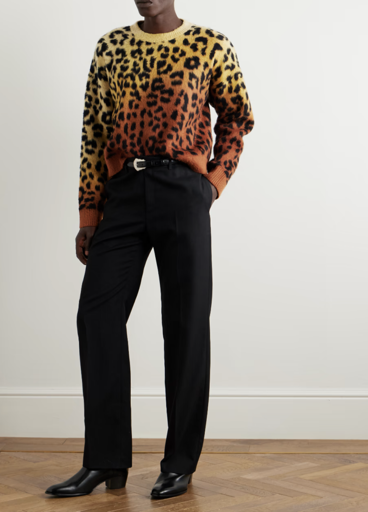 A man models a leopard print sweater and dark pants.