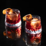 Two drinks, brown in color, sit in two rocks glasses. Esteban Cocktail