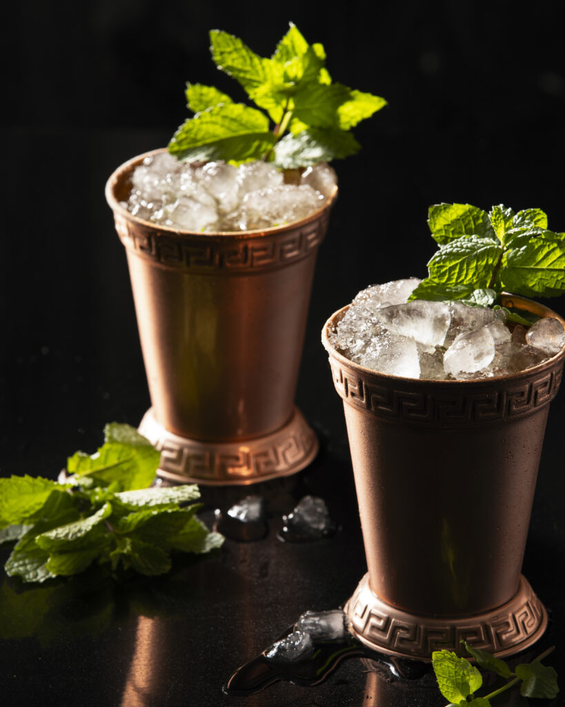 two cocktails in metal rocks cups, garnished with mint. mint julep recipe