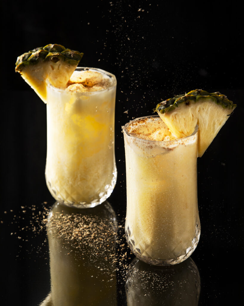 Two white yellow frozen drinks in tall, skinny glasses, PainKiller Cocktail
