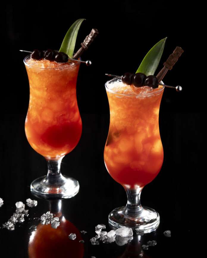 Two red and orange drinks in hurricane style glasses. Jungle Bird Cocktail