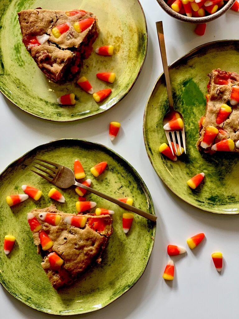Rum Pecan Candy Corn Blondies, three slices sit on three separate green plates. halloween candy