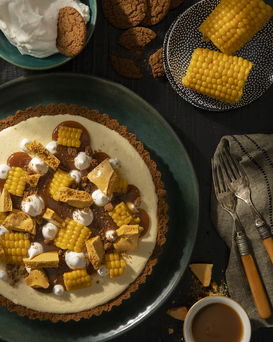An aerial shot of Sweet Corn Semifreddo on a green plate. It is covered with a caramel drizzle and small pieces of corn. Semifreddo Recipe