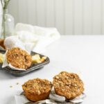 Vegan Apple Cider Muffins placed on a dish in front of a white themed backdrop.