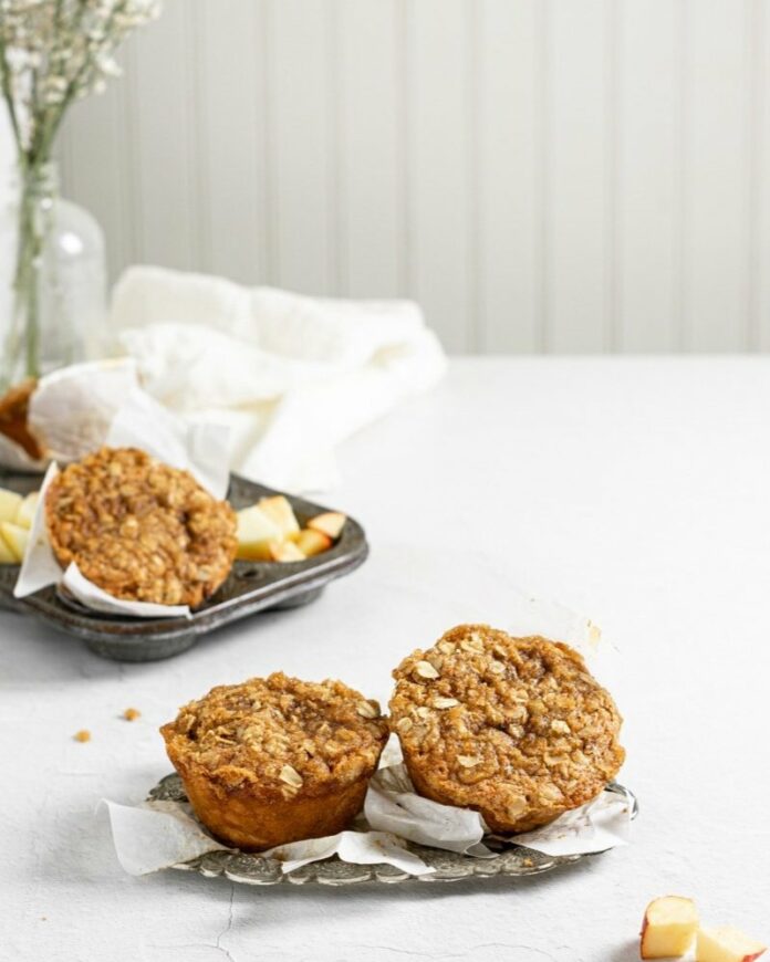 Vegan Apple Cider Muffins placed on a dish in front of a white themed backdrop.