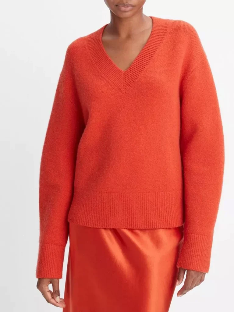 A black woman in an orange sweater from the neck down